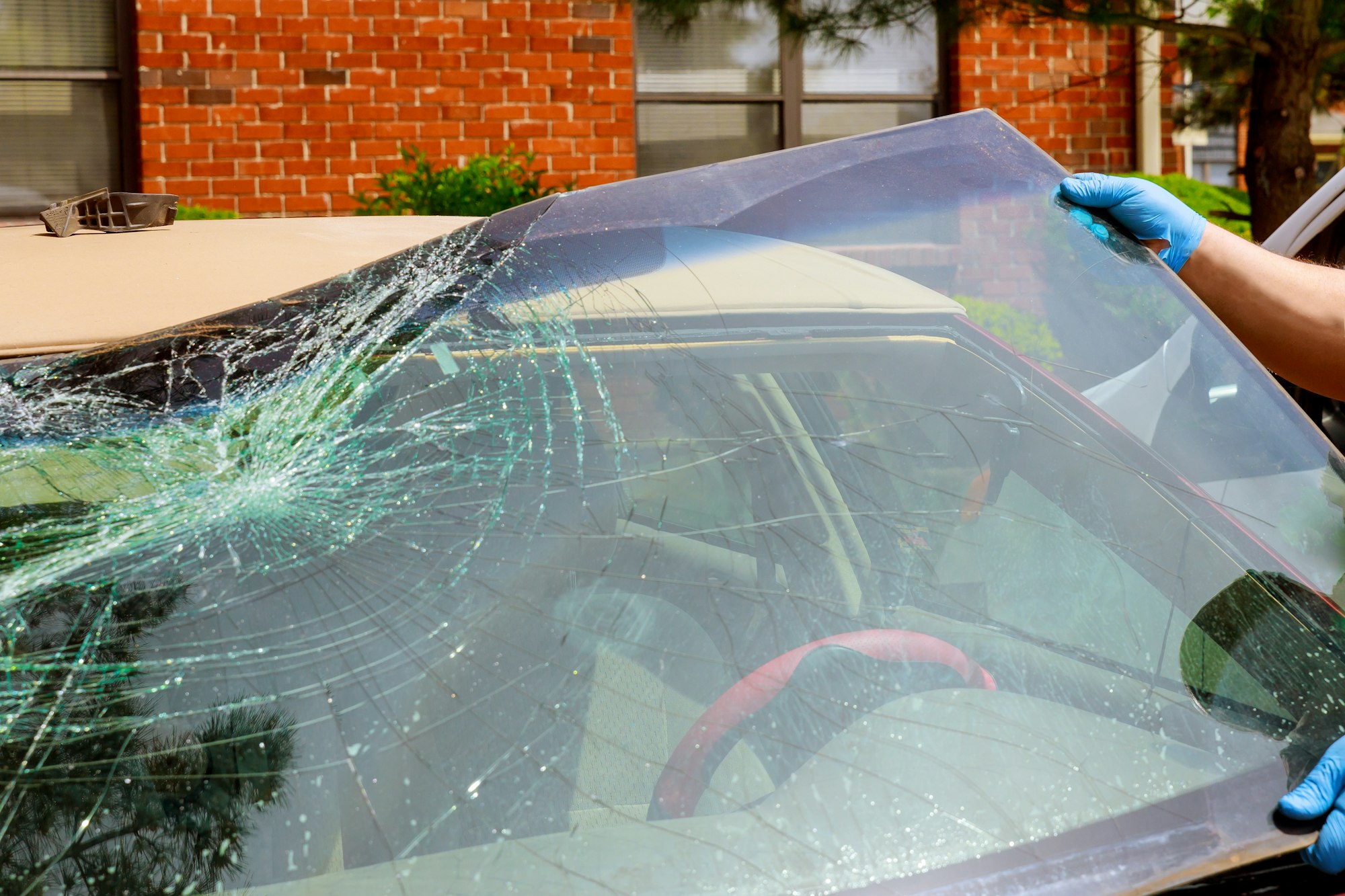 Workers remove crashed windshield of a car in auto oudoors service